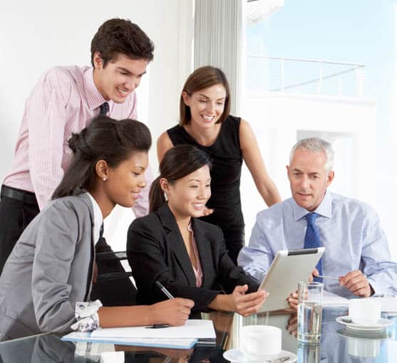 Group of business colleagues looking at a tablet in a meeting room.